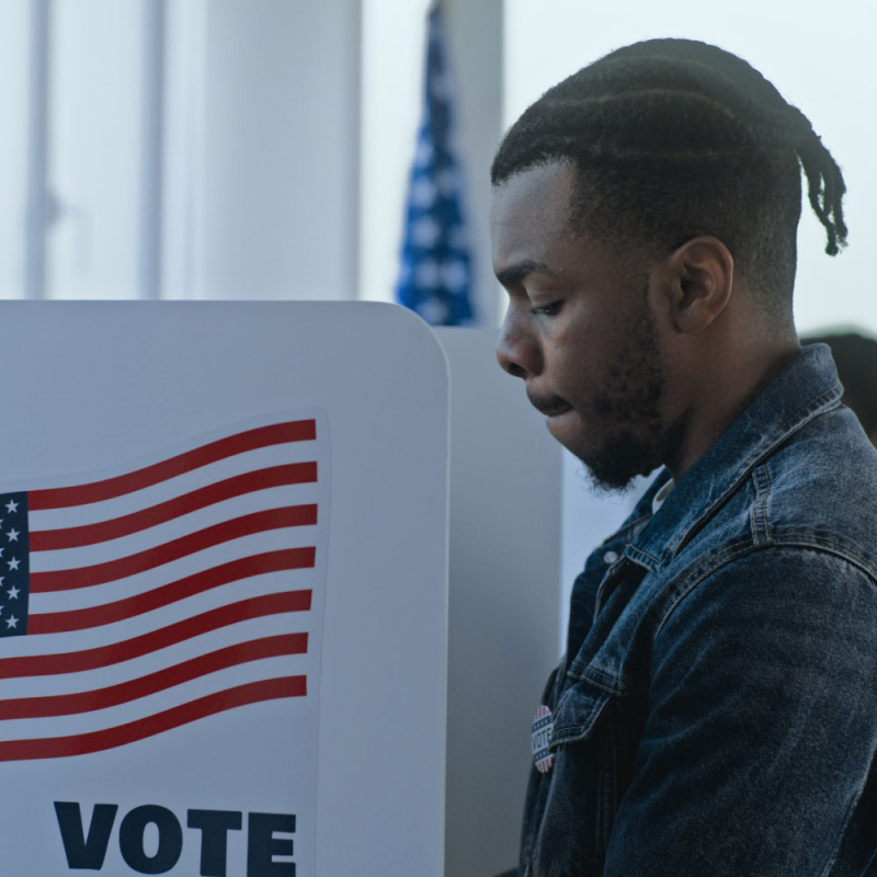 African American man stands and decides at voting booth