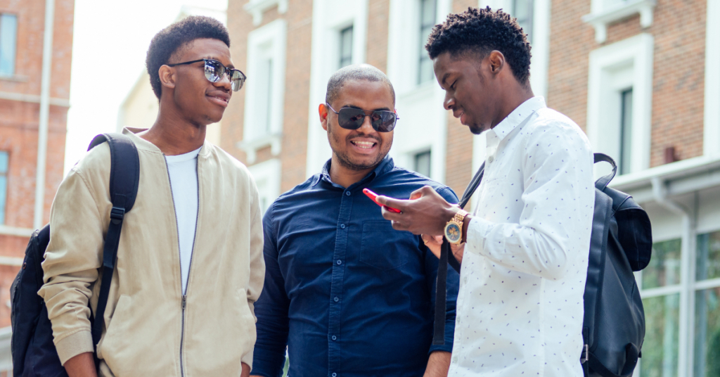 A group of three fashionable well-dressed cool African American guys students communicating on the street.