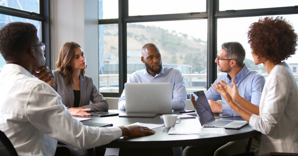 Multi-Cultural Business Team Meeting Collaborating Sitting Around Table In Modern Office Together